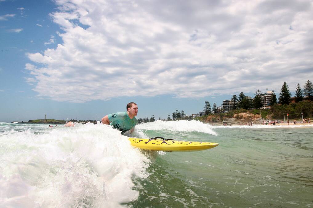 Hawks player Tim Coenraad hits the surf at Wollongong's North Beach. Picture: SYLVIA LIBER