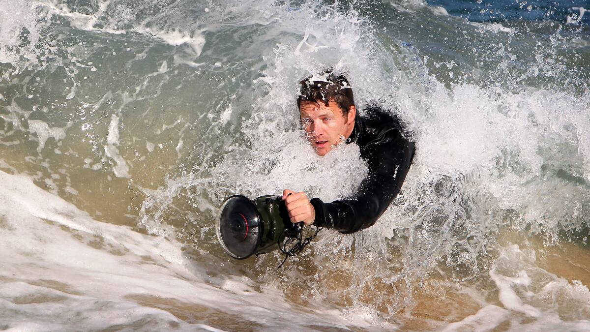 Warren Keelan in the surf with his camera at Wollongong’s City Beach yesterday. Picture: SYLVIA LIBER