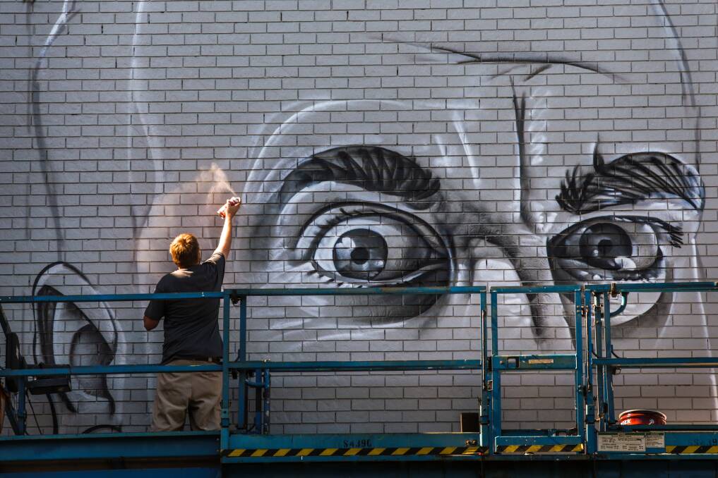 The artist known as Smug gets busy creating his wonderwall on the Wollongong Myer building. Picture: ADAM McLEAN