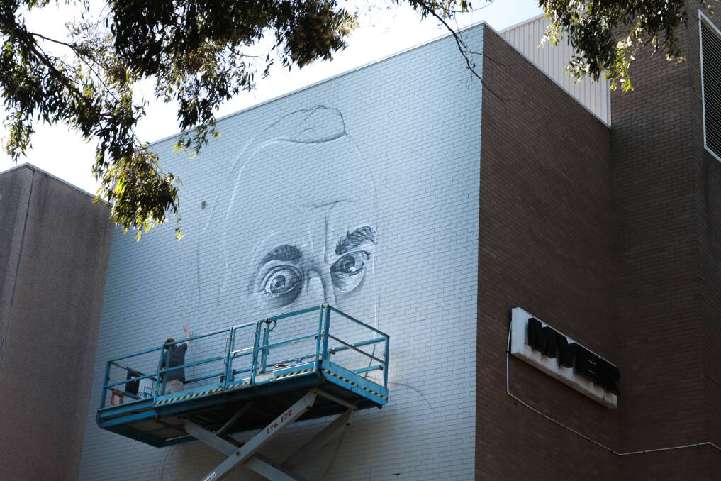 The artist known as Smug gets busy creating his wonderwall on the Wollongong Myer building. Picture: ADAM McLEAN
