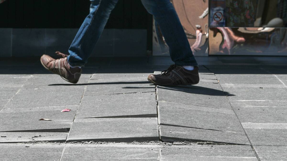 A passer-by walks over the cracks that have already appeared in the refurbished mall pavement. Picture: ADAM McLEAN