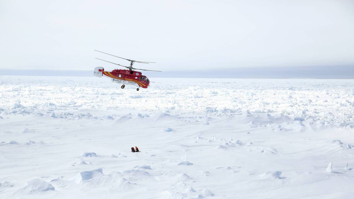 A helicopter from the Chinese icebreaker Xue Long hovers over an ice floe near the Australian icebreaker Aurora Australis, to see if it's a good place to land during the rescue mission. Picture: Nicky Phillips