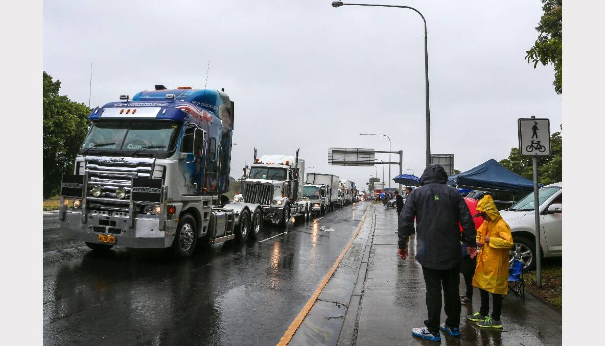 Rain-soaked spectators along Mt Ousley Road for the 2013 i98FM Camp Quality Convoy for Kids. Picture: ADAM McLEAN