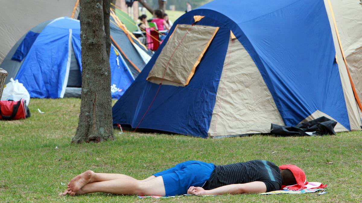A camper catches up on sleep among camp sites at Stuart Park. Pictures: KEN ROBERTSON