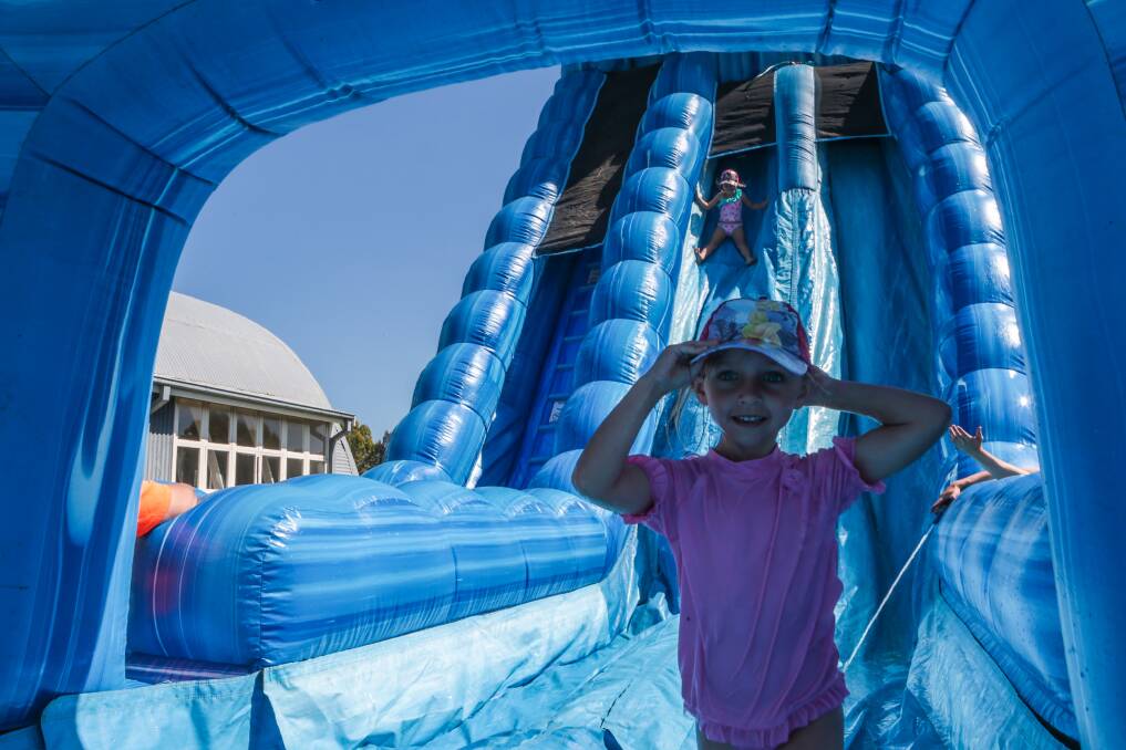 Children at the Kids' Uni vacation centre in Fairy Meadow have fun on a giant waterslide. Picture: ADAM McLEAN