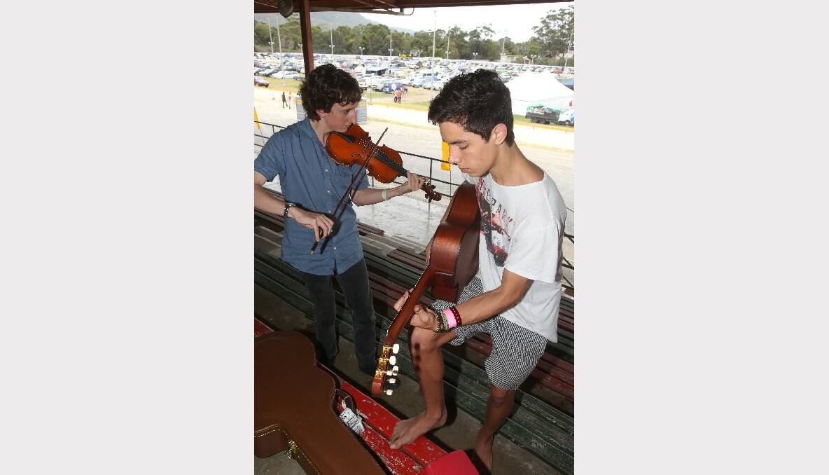 Miles Rooney, 14, (guitar) and Patrick Kelly, 18, (violin) play gypsy jazz in a quiet corner of the grandstand between their gigs.