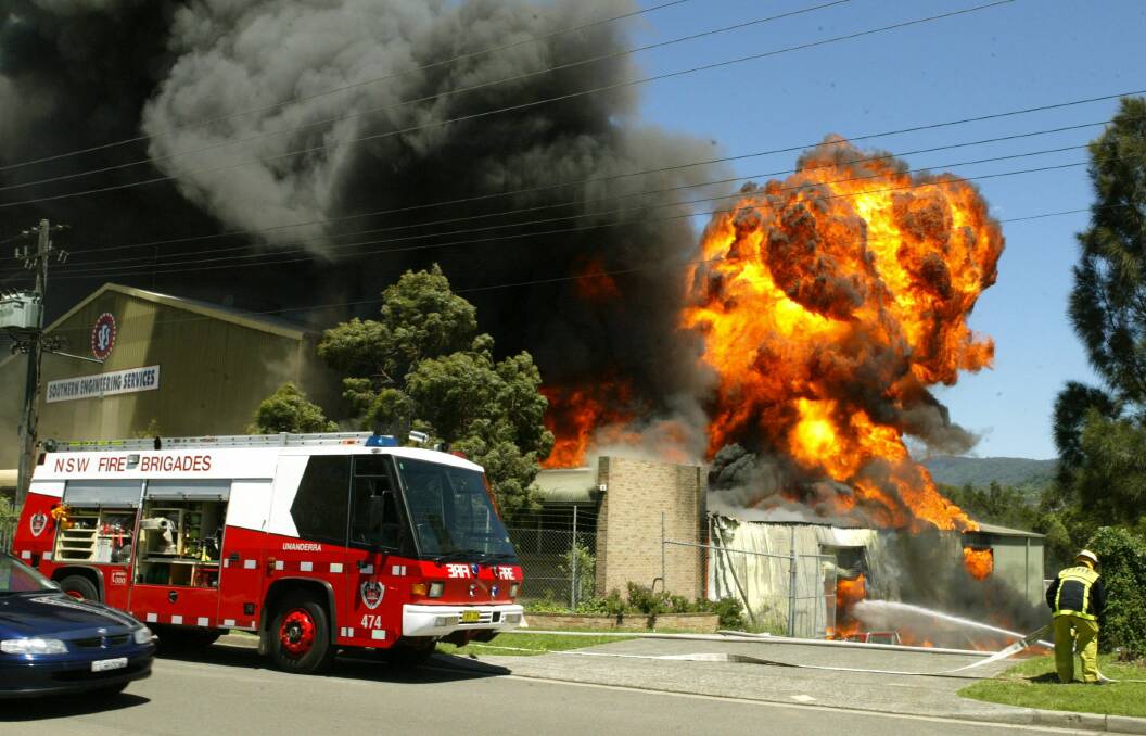 A NSW Fire Brigade vehicle arrives at a furniture business at Unanderra as a fireball erupts.