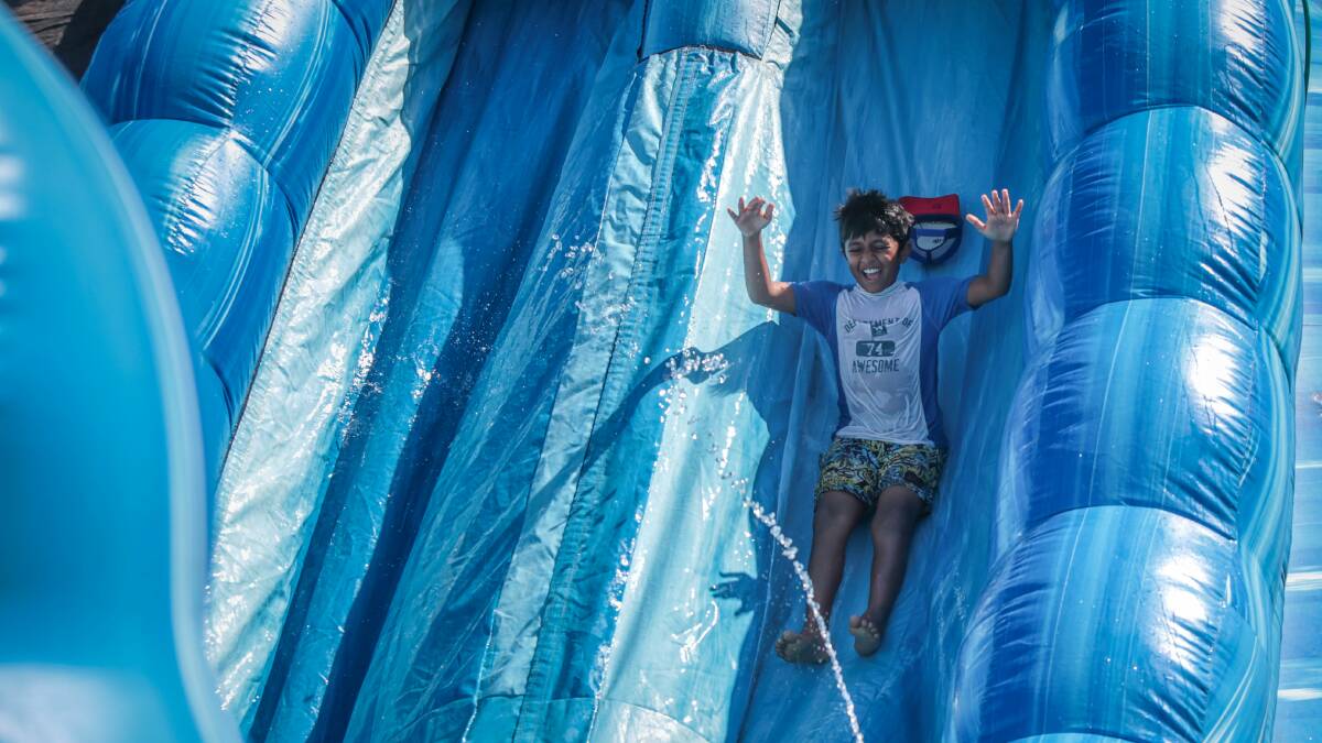 Children at the Kids' Uni vacation centre in Fairy Meadow have fun on a giant waterslide. Picture: ADAM McLEAN