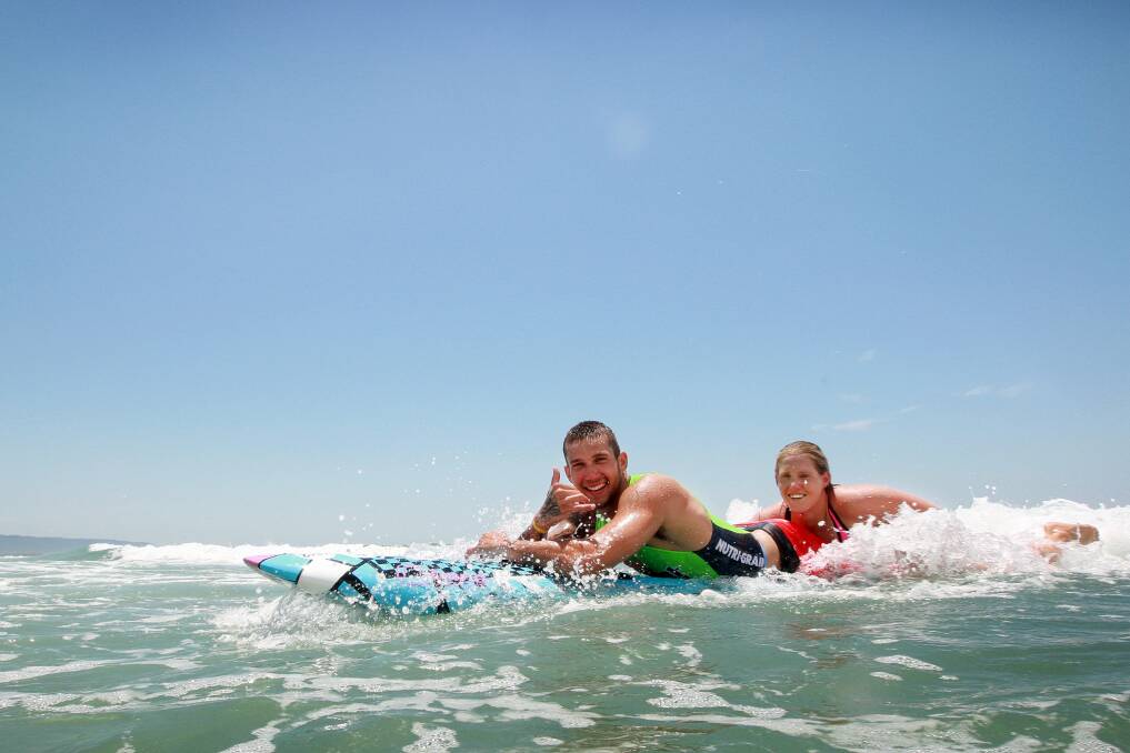 Ironwoman Hannah Minogue and Hawks player Tyson Demos hit the surf at Wollongong's North Beach. Picture: SYLVIA LIBER
