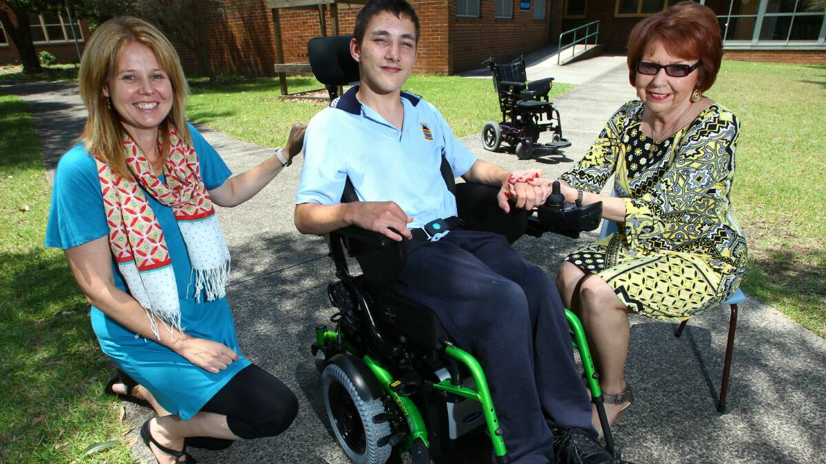 Jacob White and his new wheelchair with teacher Vanessa Cliff (left) and Chris Beaven of KidzWish. Picture: KEN ROBERTSON