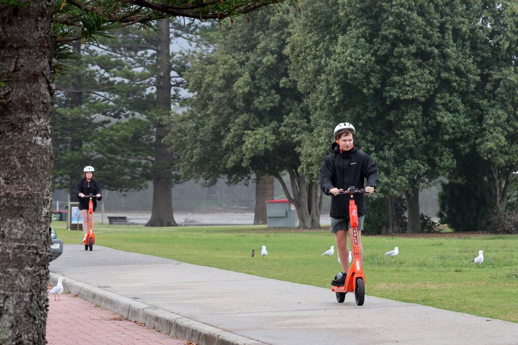 People brave the rain to ride on the e-scooters in North Wollongong on January 8, 2024. Picture by Sylvia Liber 