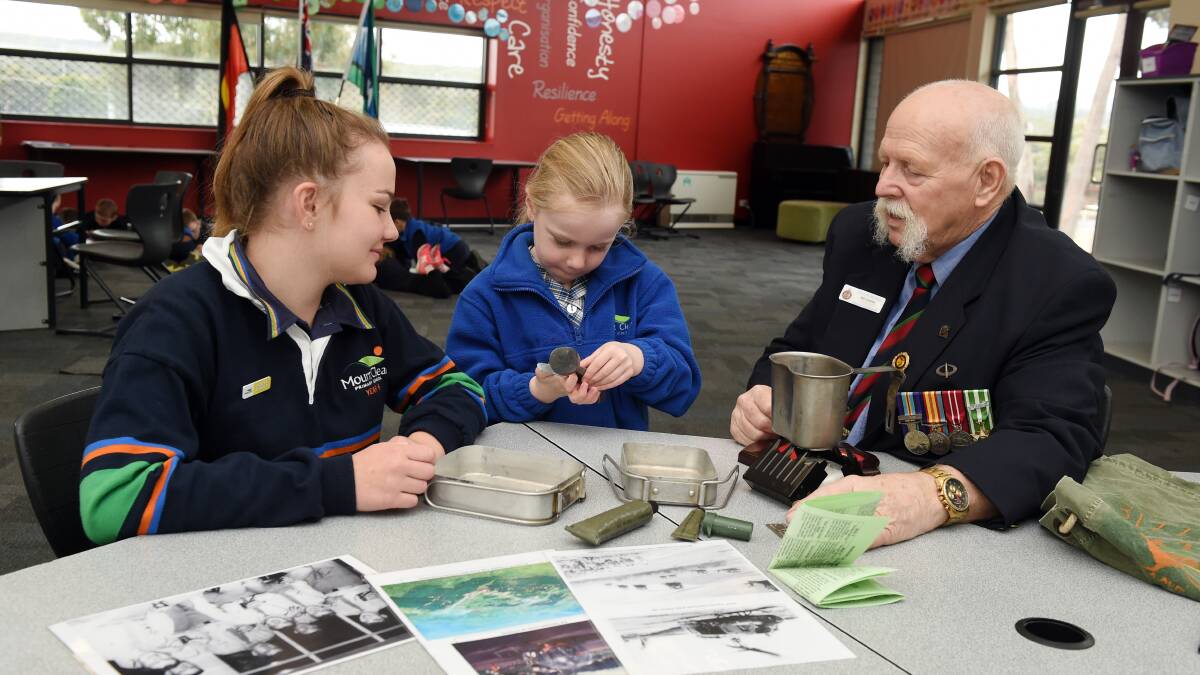 Mr Dobell showing grade six student Zara and foundation student Zara some keepsakes from his time in the army.