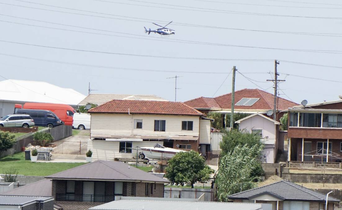 On the hunt: The PolAir chopper circles low over Warrawong. Picture: Adam McLean