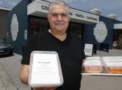 Claude Guido outside the new Villa D'Oro site in Fairy Meadow with some of the take-home packs of lasagna that kept his business afloat during COVID. Picture by Robert Peet