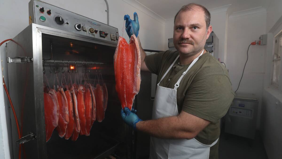 Chris Harag shows off the trout during the smoking process. Picture by Robert Peet