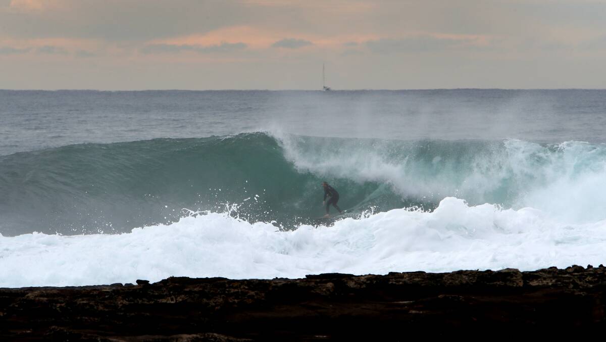 A surfer takes to the waves off Shellharbour. Picture by Sylvia Liber