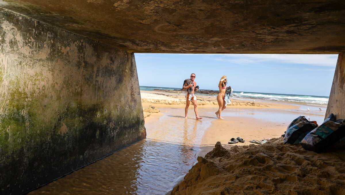 Beachgoers walk through unfiltered water from a stormwater drain that opens on to Port Kembla beach. Picture by Adam McLean