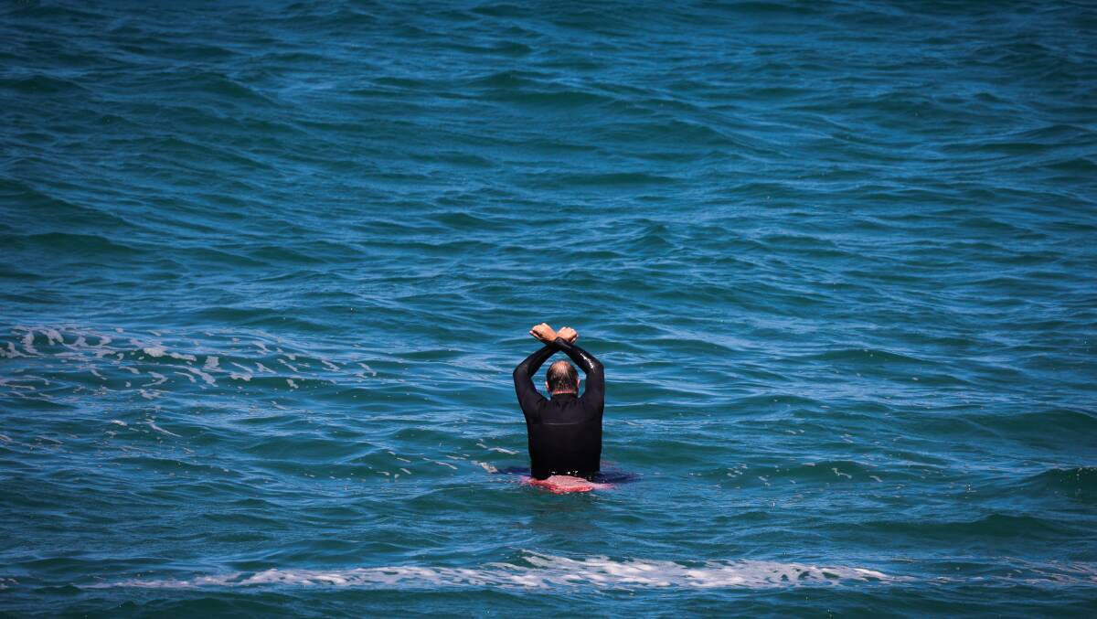 A surfer during the paddle out to oppose the Illawarra offshore wind zone. Picture by Wesley Lonergan