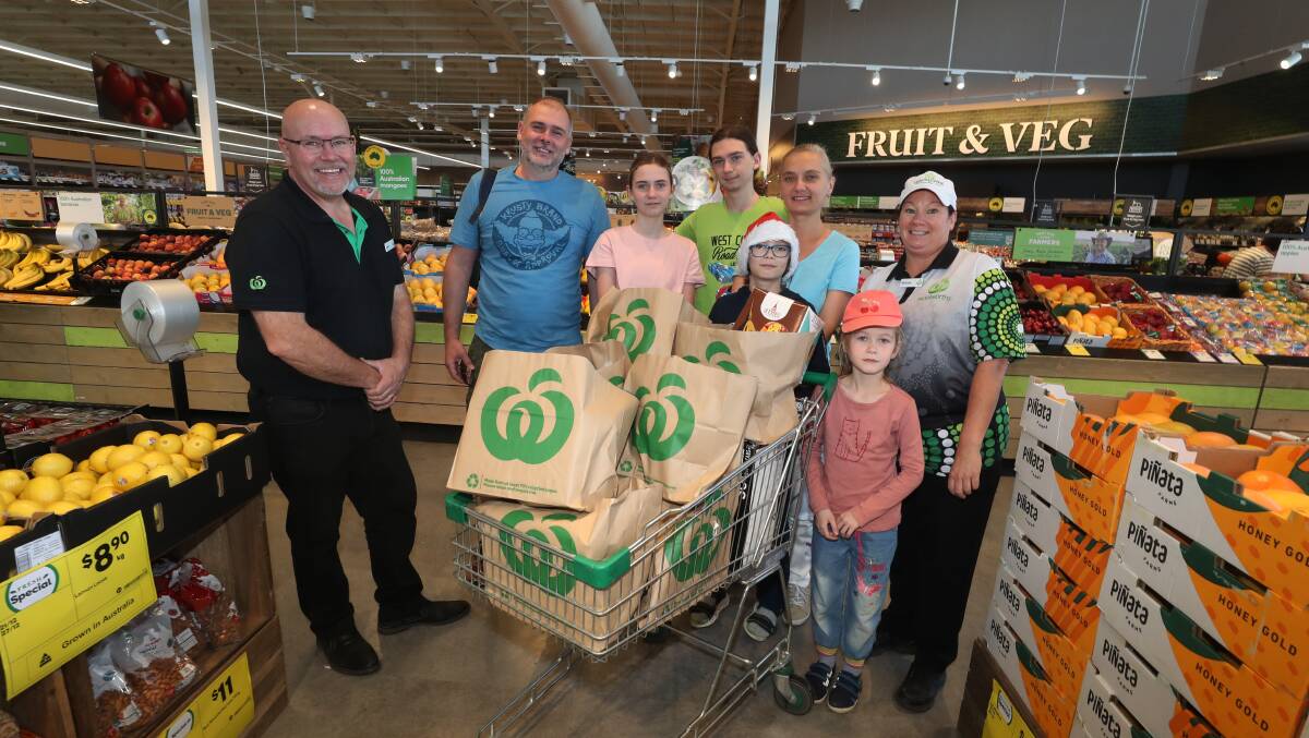 Woolworths Shell Cove store manager Jason Hall with the Kondratenko family Oleksii, Varvara, Illia, Mark, Nataliia and Liza with Woolworths Shell Cove bakery team leader Michelle Lumsden. Picture by Robert Peet.