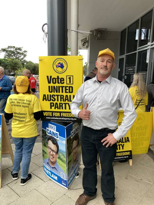 UAP candidate Allan Wode stands proudly next to the bright yellow signs