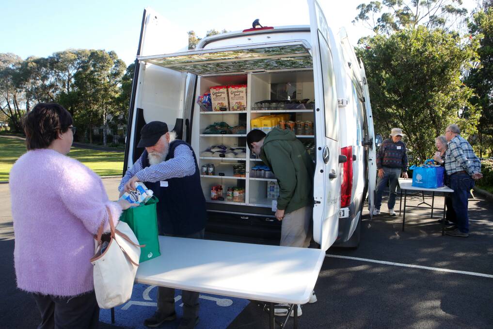 Volunteers Tony Michel and Jake Parker handing out food at the Anglicare Mobile Pantry in Shellharbour. Picture:Sylvia Liber