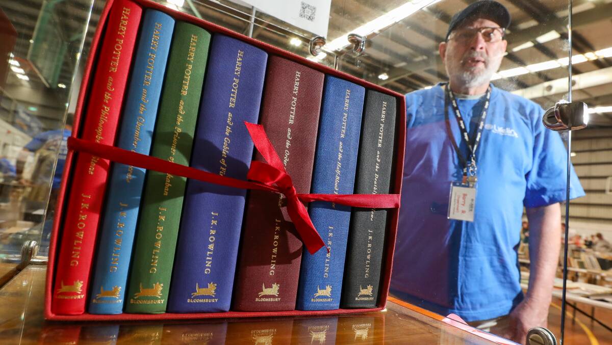 Volunteer supervisor of old books Barry Ridding with the first edition harry potter hardcover set selling for $1400 at the lifeline book fair in the Berkeley Indoor sports centre. Picture by Adam McLean