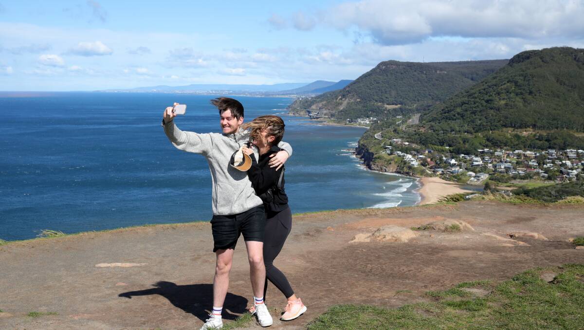 Jake Baker from Sydney and Olivia Kight from Texas pose for a photo in the windy weather at Bald Hill on August 18, 2023. Picture by Sylvia Liber
