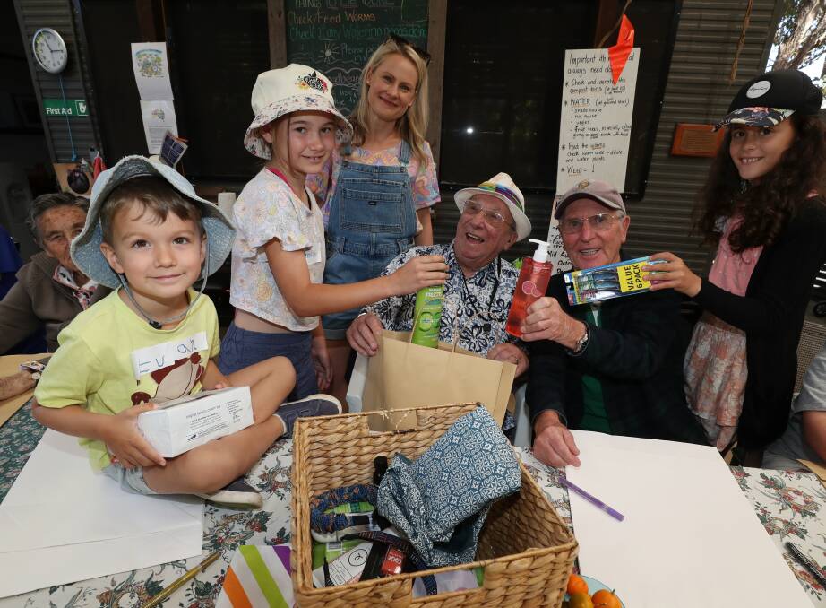 Four-year-old Evan Haldane, 11-year-old Savannah Hedstrom, Family OOSH director Sabrina Kelly, Bluehaven clients George Robertson and Jim Spence and 11-year-old Alonna Webb pack bags of donated goods for rural communities. Picture by Robert Peet