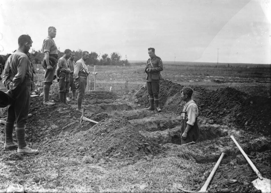HIGHER POWER: 20th Battalion chaplain Captain Robert Crawford, from Toowong, Queensland, conducting a burial service near Péronne on August 31, 1918. Picture: AWM E03092