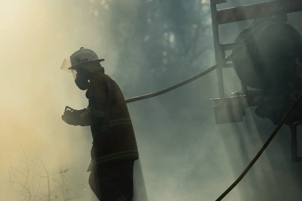 August 15: A Rural Fire Service volunteer fights a fire behind properties on the Princes Highway in Bomaderry. Picture: Adam McLean 