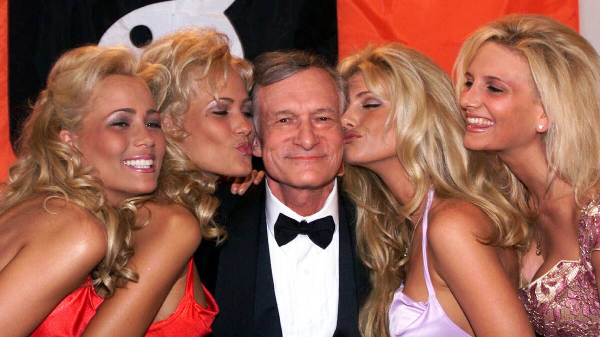 Playboy founder and editor in chief Hugh Hefner receives kisses from Playboy playmates during the 52nd Cannes Film Festival in Cannes, France in 1999. Picture: AP