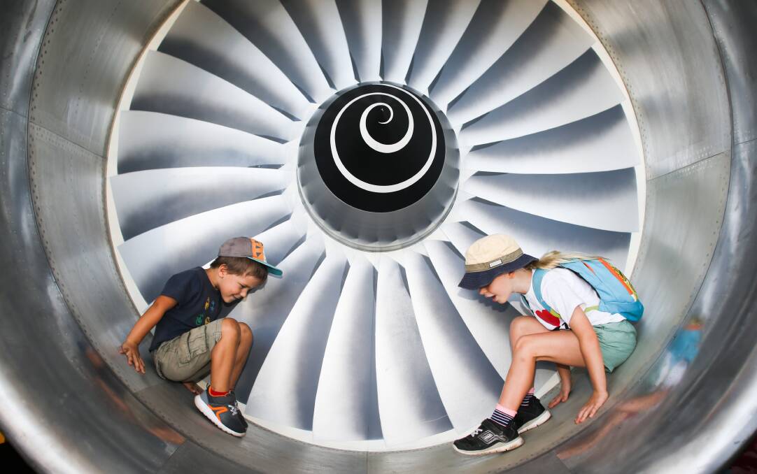 Peter Cheremisemov and Marsha Cheremisemova play in a jet engine inlet at the Wings over the Illawarra air show at Illawarra Regional Airport. Picture: Georgia Matts
