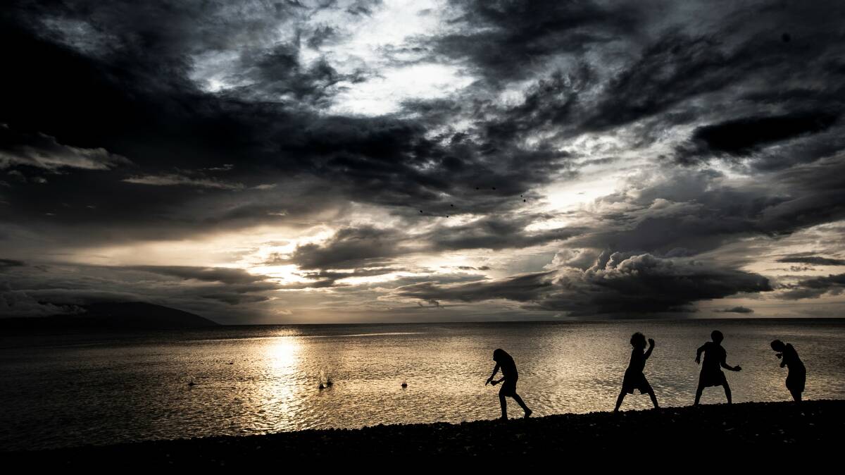 Young boys from Ambae throw stones in the direction of the volcanic island. Picture: Paul Jones
