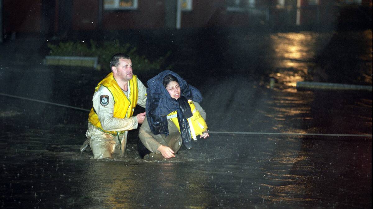 Police rescue officer Senior Constable Gary Storey rescues a woman from rising flood waters on Pioneer Road, Towradgi.