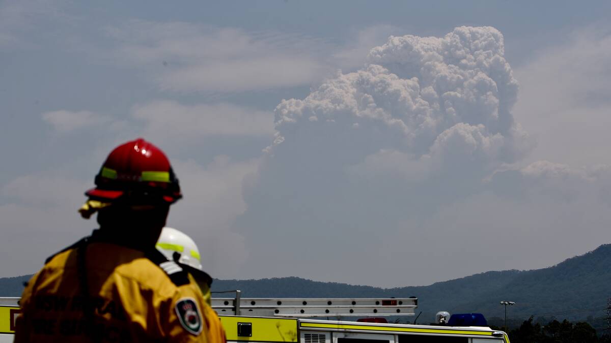 A firefighter at Berkeley watches a large fire cloud from the Wollondilly fire. Picture: Adam McLean