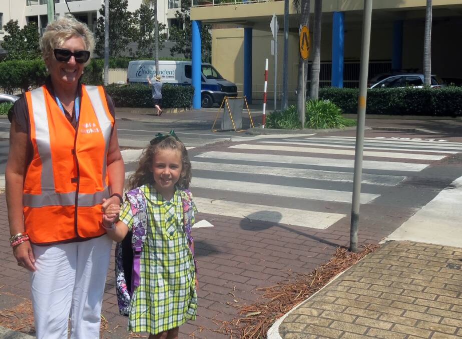 Road Safety Officer Janelle Burns helps Ava cross the road safely on Manning Street, Kiama.