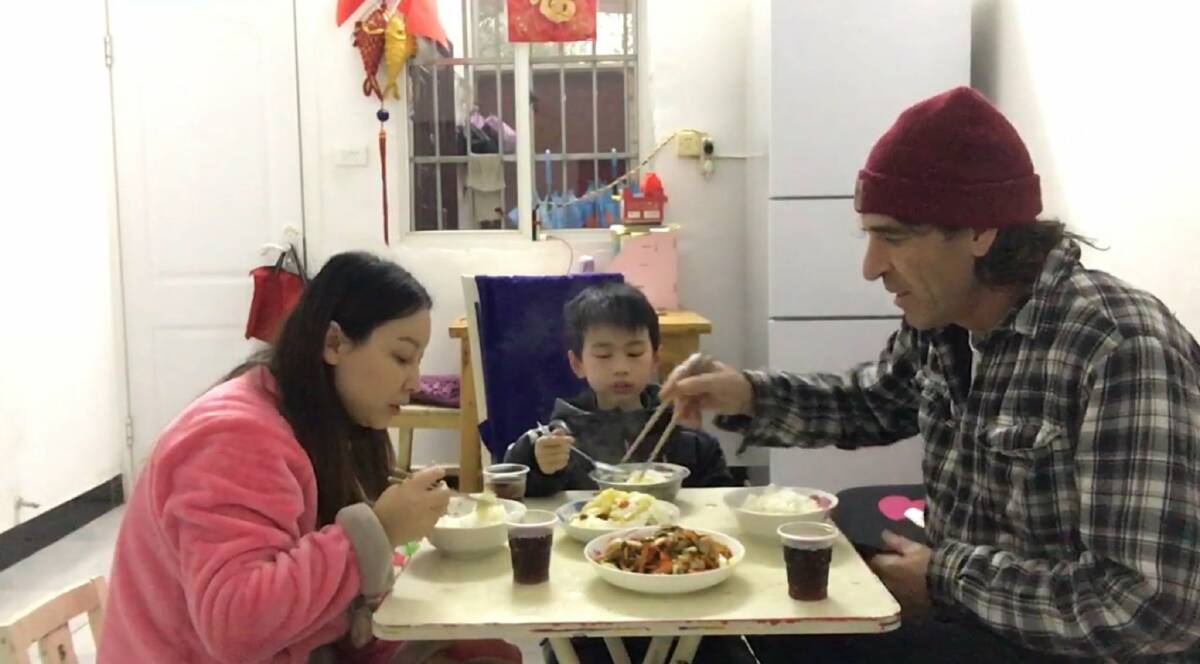 MEAL TIME: Xu Qiong, her son Weichen and Tim McLean in the Ezhou apartment in which they've been locked down since late January.