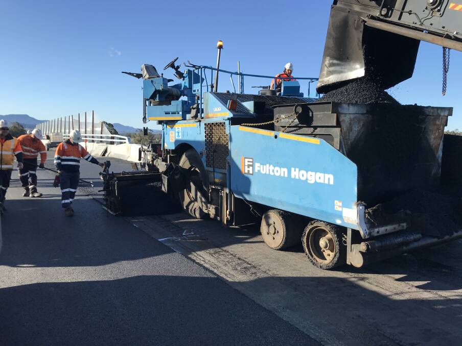 Drive on: Fulton Hogan workers laying asphalt on the Albion Park Rail bypass, which includes glass. Picture: Transport for NSW