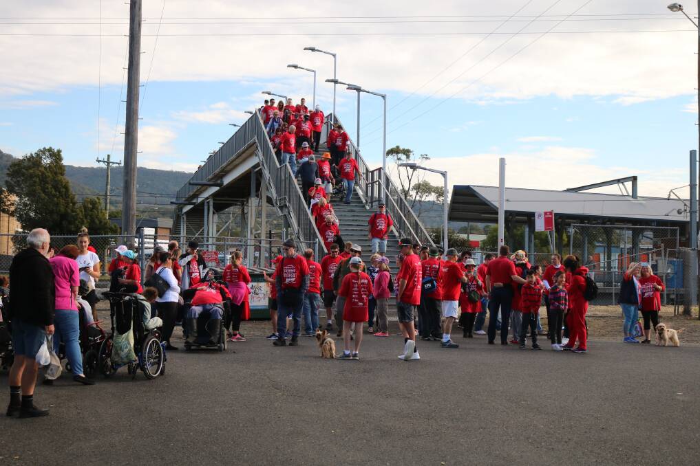 Some of the more than 150 red-clad walkers arrive at Unanderra station during an event to continue the campaign for lift access. Picture: supplied