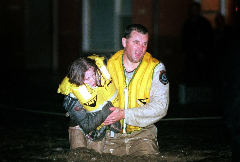 Police rescue officer Senior Constable Gary Storey rescues Ashlie Hawkes from rising flood waters on Pioneer Road, Towradgi, in one of the most iconic images of the 1998 storms.