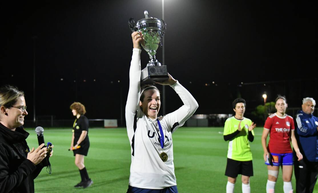 University captain Elise Battin lifts up the trophy after her side won this year's Women's Division One grand final. Picture by Richie Wagner