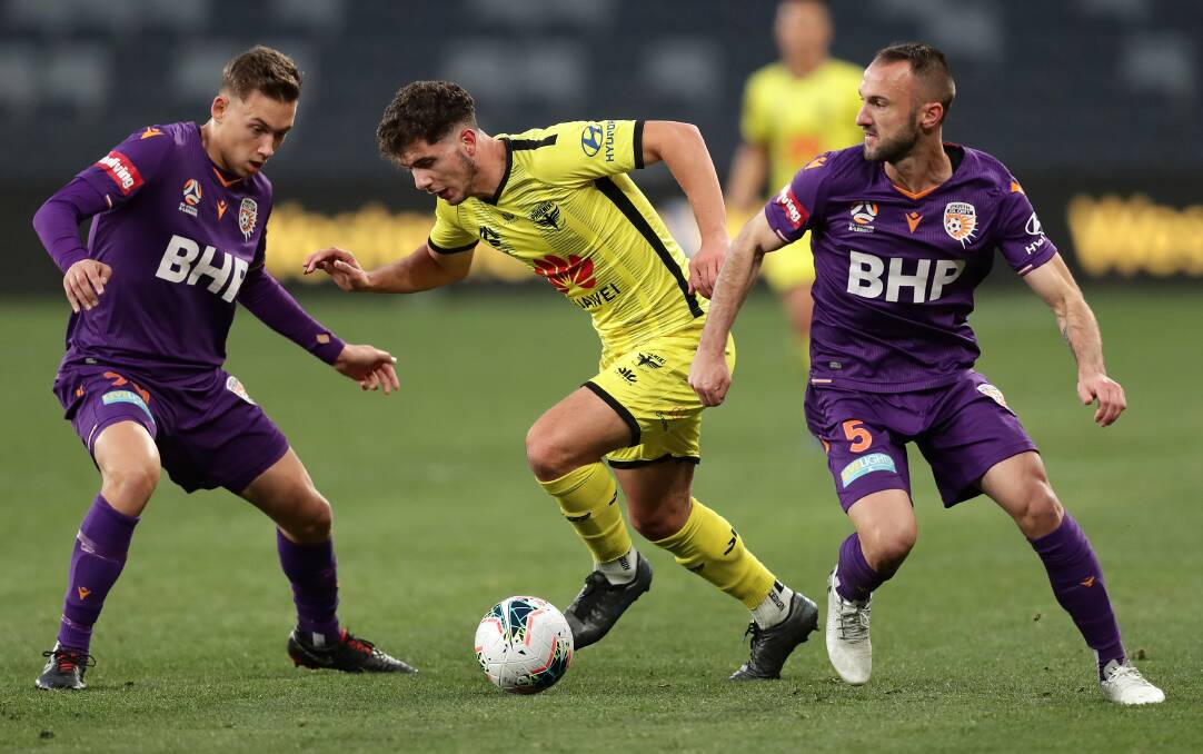 ON THE MOVE: Phoenix player Liberato Cacace gets the ball between two Perth defenders during a game last season. Picture: Mark Metcalfe/Getty Images