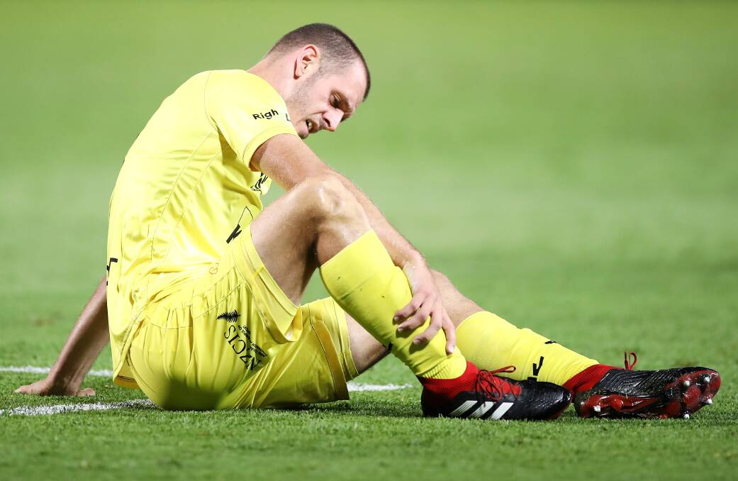 DOWN: Wellington Phoenix defender Luke DeVere grabs his leg after suffering an injury. Picture: Mark Kolbe/Getty Images
