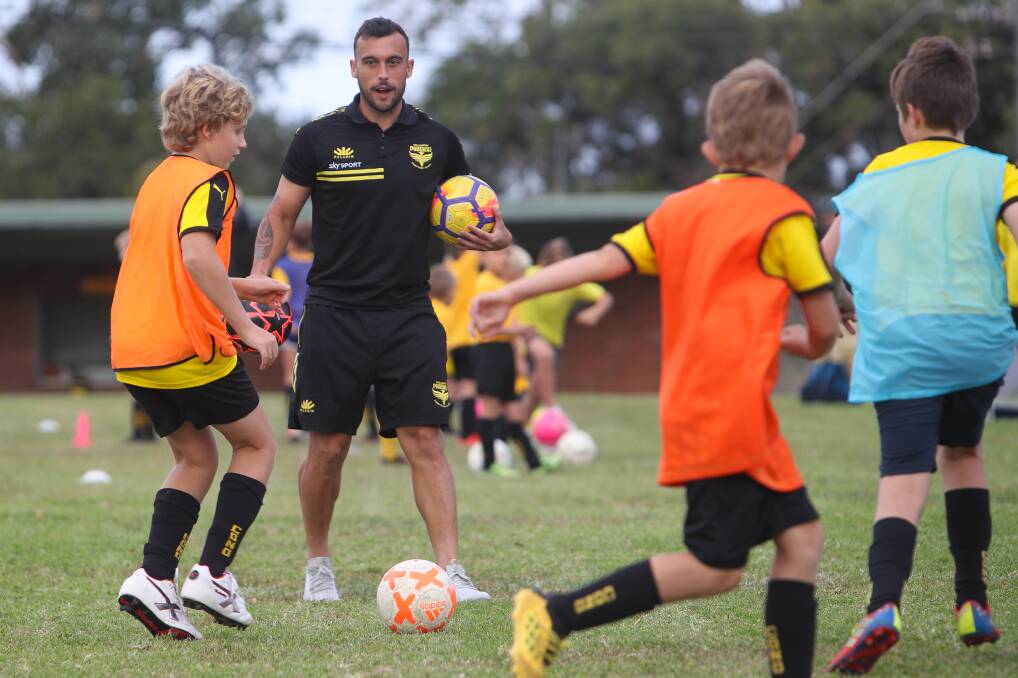 SUPPORT PLAY: Wellington Phoenix midfielder Clayton Lewis helps run a junior coaching clinic in Coniston on Friday. Picture: Adam McLean