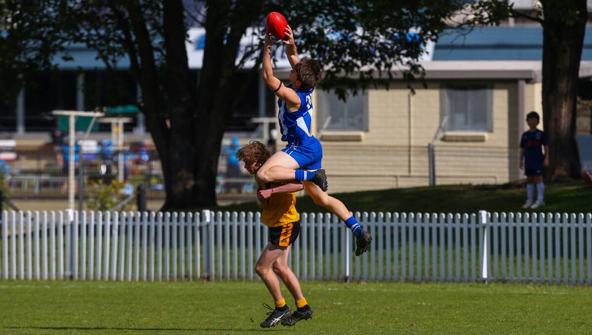 STANDING TALL: Figtree's Will Foster flies high to take a big mark over his Tigers opponent. Picture: Wesley Lonergan