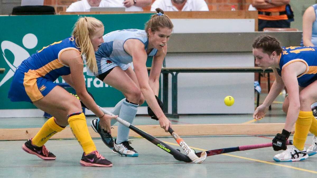 CHALLENGE: Three players compete for the ball during an indoor hockey game in Wollongong. Picture: Adam McLean