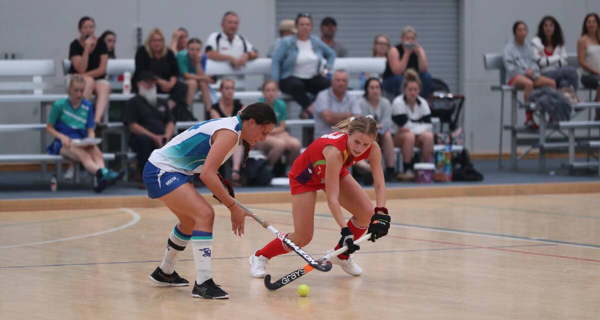 DETERMINED: Woonona teen Brooke Welsh (right) challenges for ball possession during a recent indoor hockey game for Illawarra South Coast.