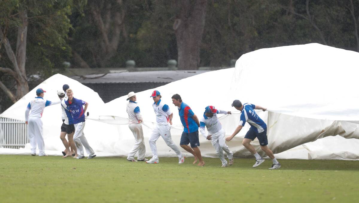 HARD WORK: Uni and Wests cricketers cover the pitch as the rain falls last season. Picture: Adam McLean