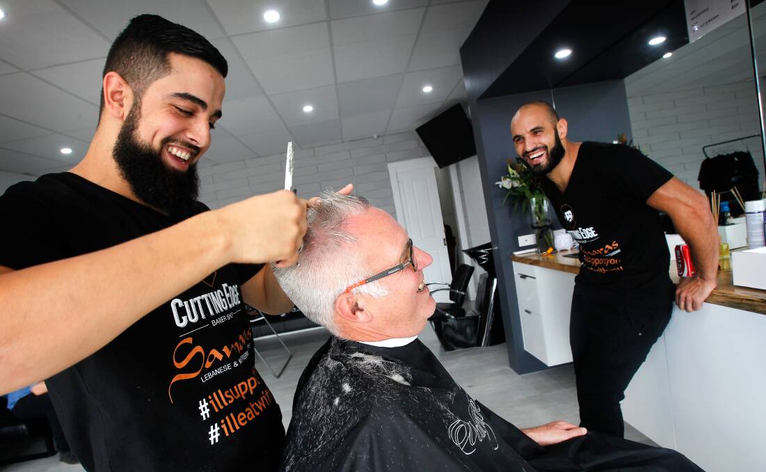 United: Lifeline director Graham Gould getting hair cut by Bilal El-Mohamad and Omar Nemer. The Unanderra barber shop has been the target of vandals.