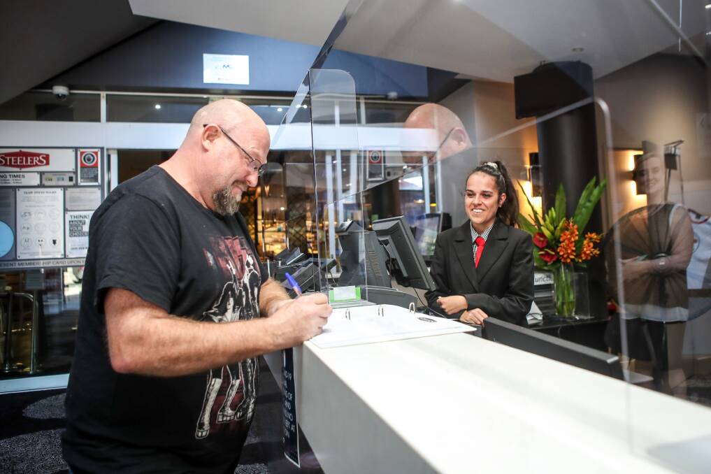 Sneeze shields in place: Andrew Buckingham was one of many signing in at the Steelers club front desk after receiving advice from employee Shayla Windley. The club opened for the first time in months on Monday. Picture: Adam McLean